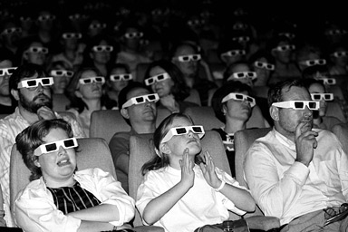 An audience watches a film through 3D glasses.