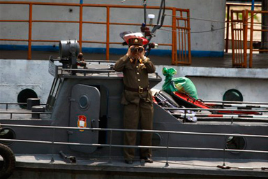 A North Korean soldier monitors a Chinese tour boat with binoculars along the Yalu River dividing China and North Korea near Dandong, northeastern China's Liaoning province, Wednesday, May 27, 2009.
