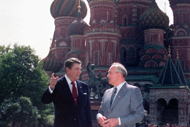 Top: U.S. President Ronald Reagan, left, and Soviet leader Mikhail Gorbachev stand alone during their impromptu walk in Red Square in Moscow, USSR, Tuesday, May 31, 1988. In the background is St. Basil's Cathedral. Bottom: East German border guards look through a hole in the Berlin wall after demonstrators pulled down one segment of the wall at Brandenburg gate in this November 11, 1989 picture.
