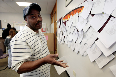 Unemployed truck driver Allen Askew III gestures to the photographer while checking job listings at a jobs search agency in Detroit, Michigan April 3, 2009.