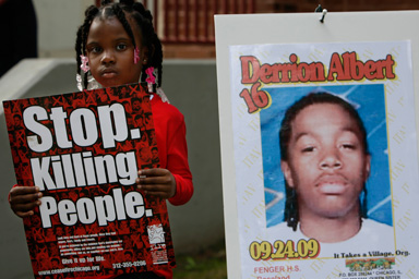 Nadashia Thomas, 6, a cousin of Derrion Albert, holds a sign beside a poster of Derrion Albert at Fenger High School in Chicago, Sept. 28, 2009.