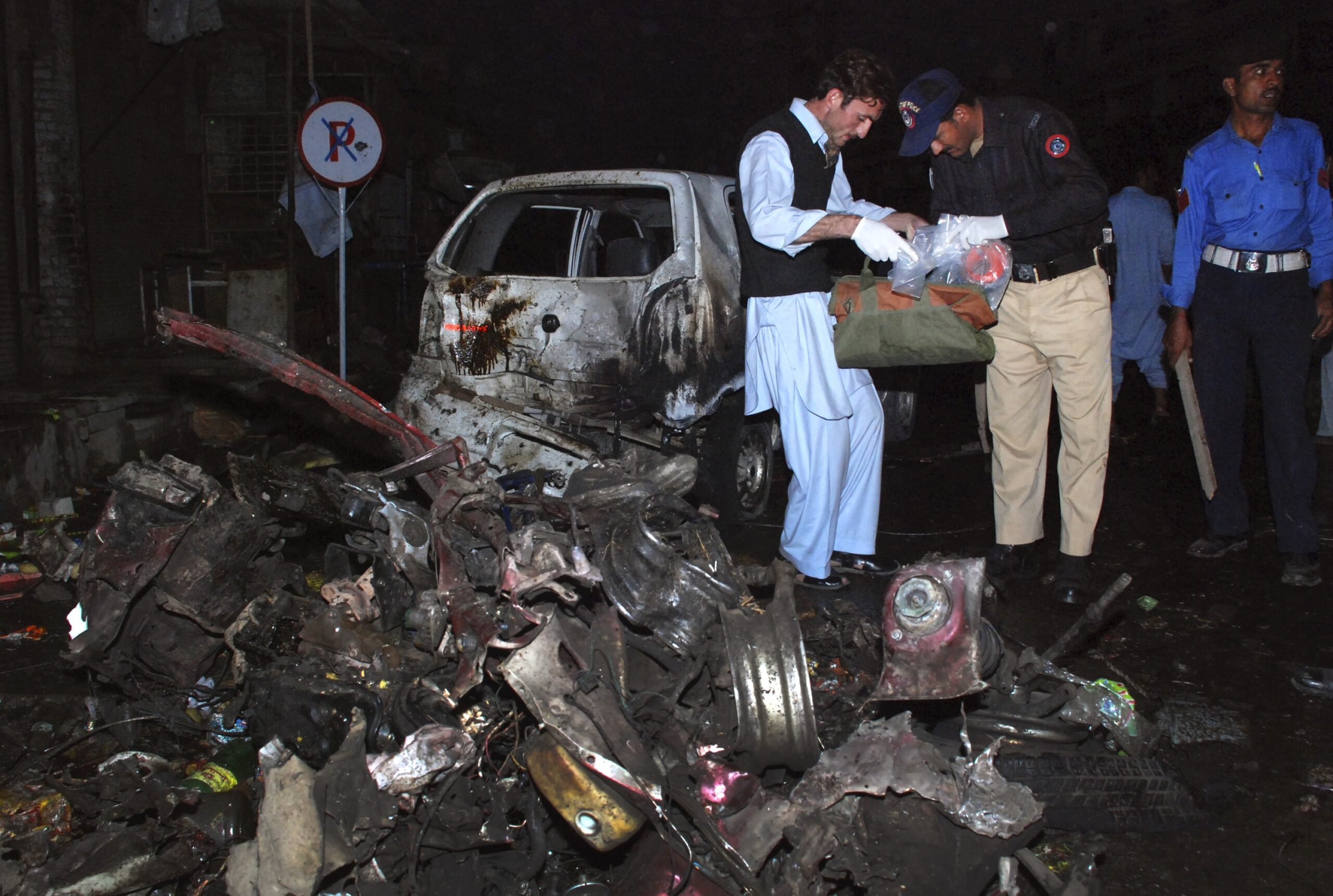 Police officials survey the site of a suicide bomb explosion in Charsadda, located about 20 km (12 miles) northeast of Peshawar November 10, 2009. Pakistani Taliban militants vowed to fight a tough, protracted guerrilla war against the army on Tuesday as a suicide car-bomber killed up to 20 people in a northwestern town, police said. A suicide bomber in a car set off explosives in a square in the centre of Charsadda killing up to 20 people and wounding at least 30, town police chief Riaz Khan said.  REUTERS/K Parvez  (PAKISTAN CONFLICT) (Reuters)