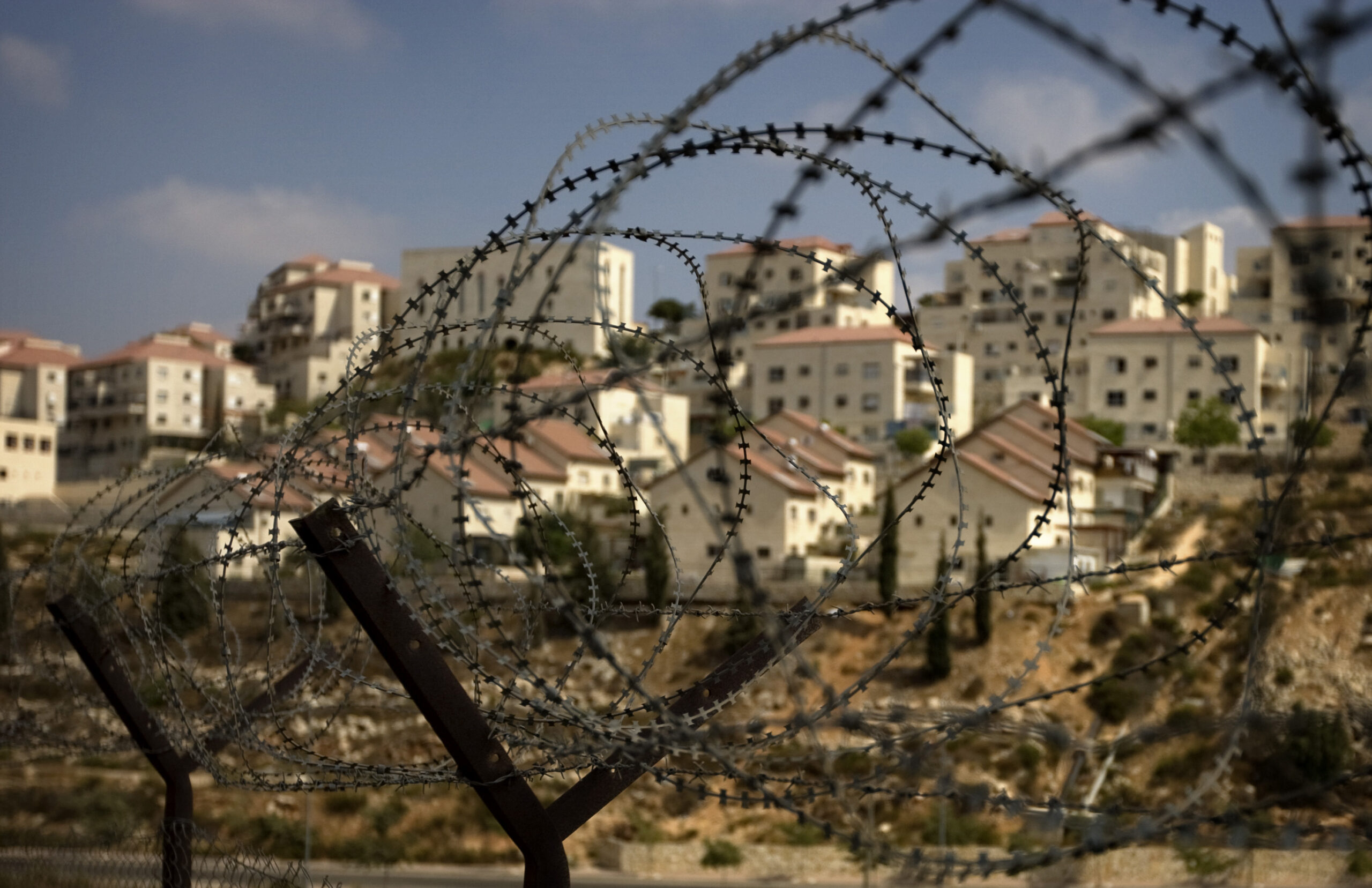The West Bank Jewish settlement of Beitar Ilit is seen through a barbed wire fence, Friday, Sept. 4, 2009. Prime Minister Benjamin Netanyahu is expected to  approve some hundreds of new housing units in West Bank settlements before slowing settlement construction, two of his aides said Friday, in an apparent snub of Washington's public demand for a total settlement freeze.  (AP Photo/Sebastian Scheiner) (Associated Press)