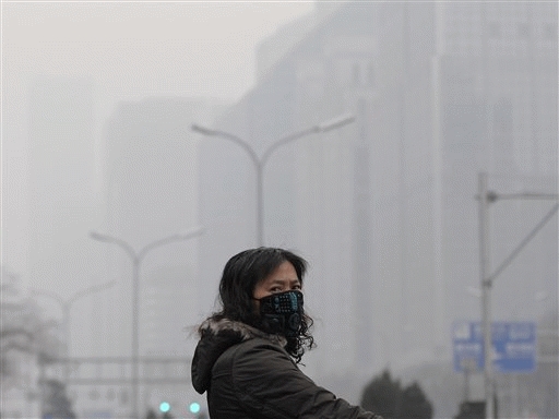 A masked woman looks away while crossing a street in the city center shrouded in fog, caused by air pollution, in Beijing Monday. Negotiators in Copenhagen are trying to set targets for controlling emissions of carbon dioxide and other global warming cases, including by the leading contributors, China and the United States.
