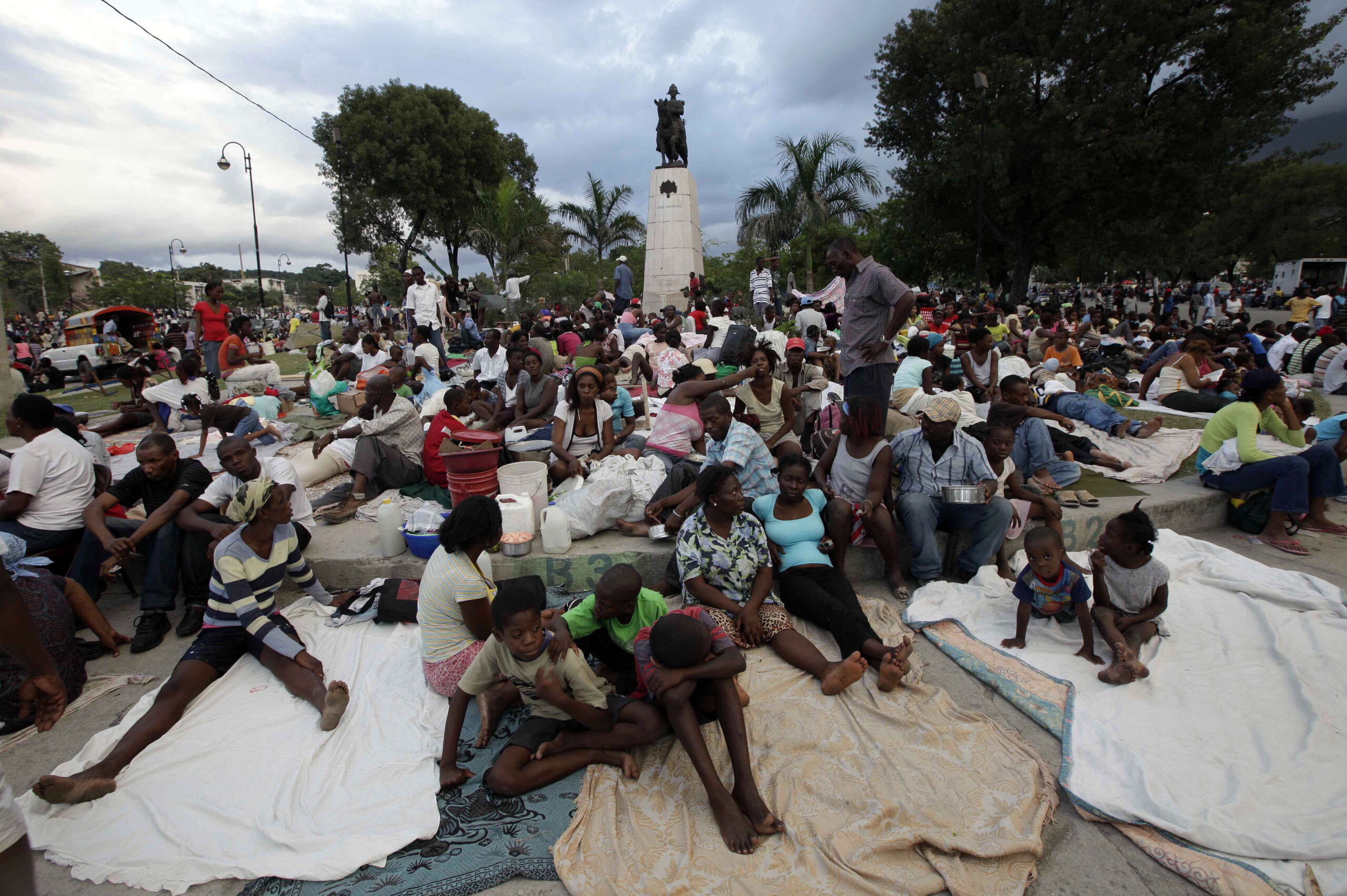 People sit at a park a day after the destructive earthquake in downtown Port-au-Prince, Wednesday, Jan. 13, 2010. The 7.0-magnitude earthquake that hit Haiti on Tuesday flattened the president's palace, the cathedral, hospitals, schools, the main prison and whole neighborhoods. (AP Photo/Gregory Bull) (Associated Press)