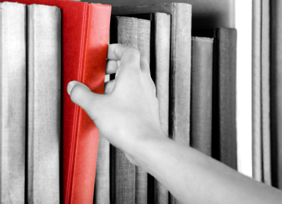 Image of a hand selecting a red book from a bookshelf (Andreas G. Karelias)
