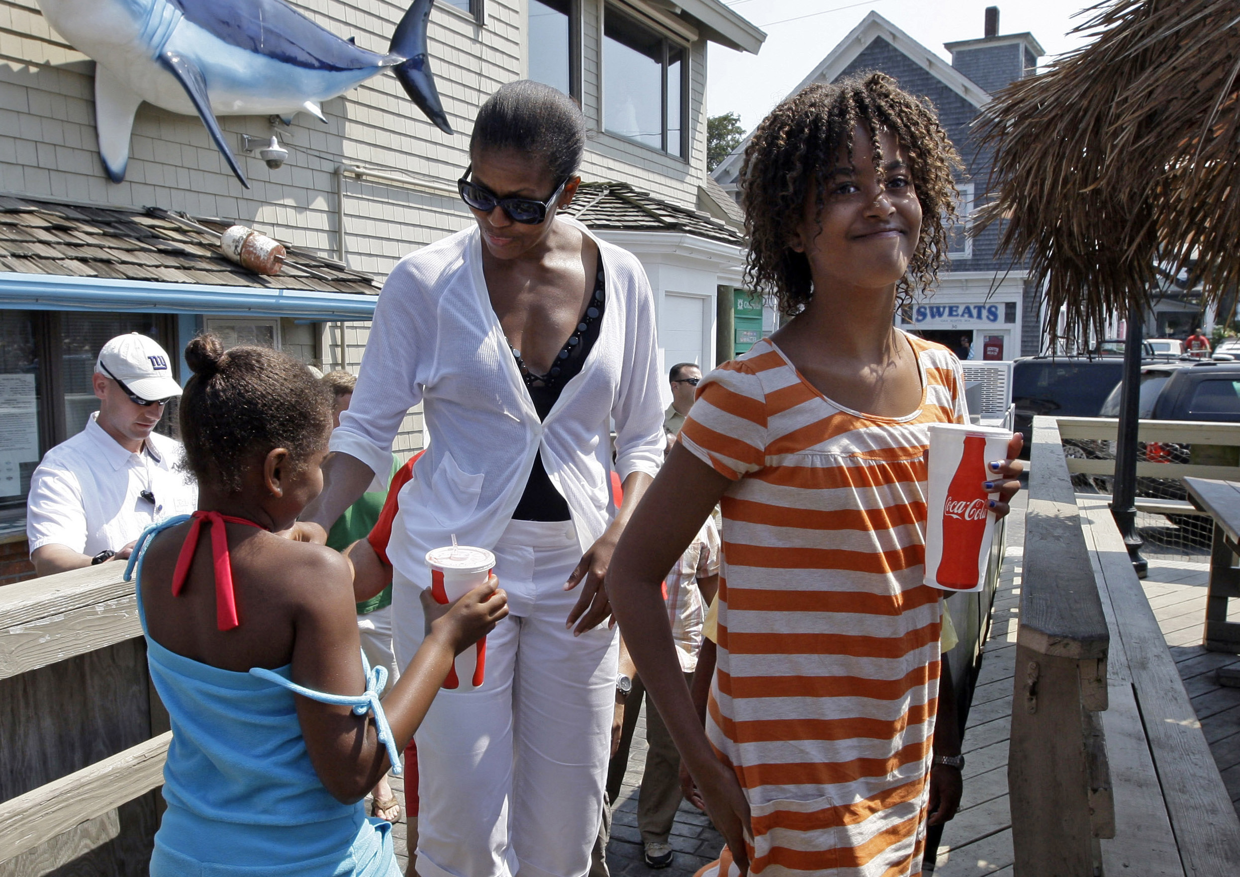 FILE - In this Aug. 26, 2009, file photo, first lady Michelle Obama walks with daughter Malia, 11, right, and Sasha, 8, while they wait to get lunch at Nancy's in Oak Bluffs, Mass., while vacationing on Martha's Vineyard. (AP Photo/Alex Brandon, File) (Associated Press)