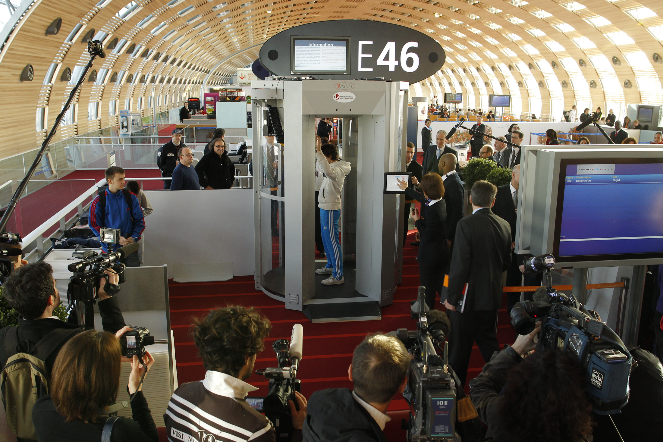 A security official (2nd R) prepares to scan a man posing inside a full-body scanner being trialled by Roissy Charles-de-Gaulle airport during a photocall at the departure gate in Roissy near Paris February 22, 2010. France will use body scanners at some of its airports, initially to search passengers heading to the United States.  REUTERS/Benoit Tessier  (FRANCE - Tags: TRAVEL TRANSPORT CRIME LAW) (Reuters)
