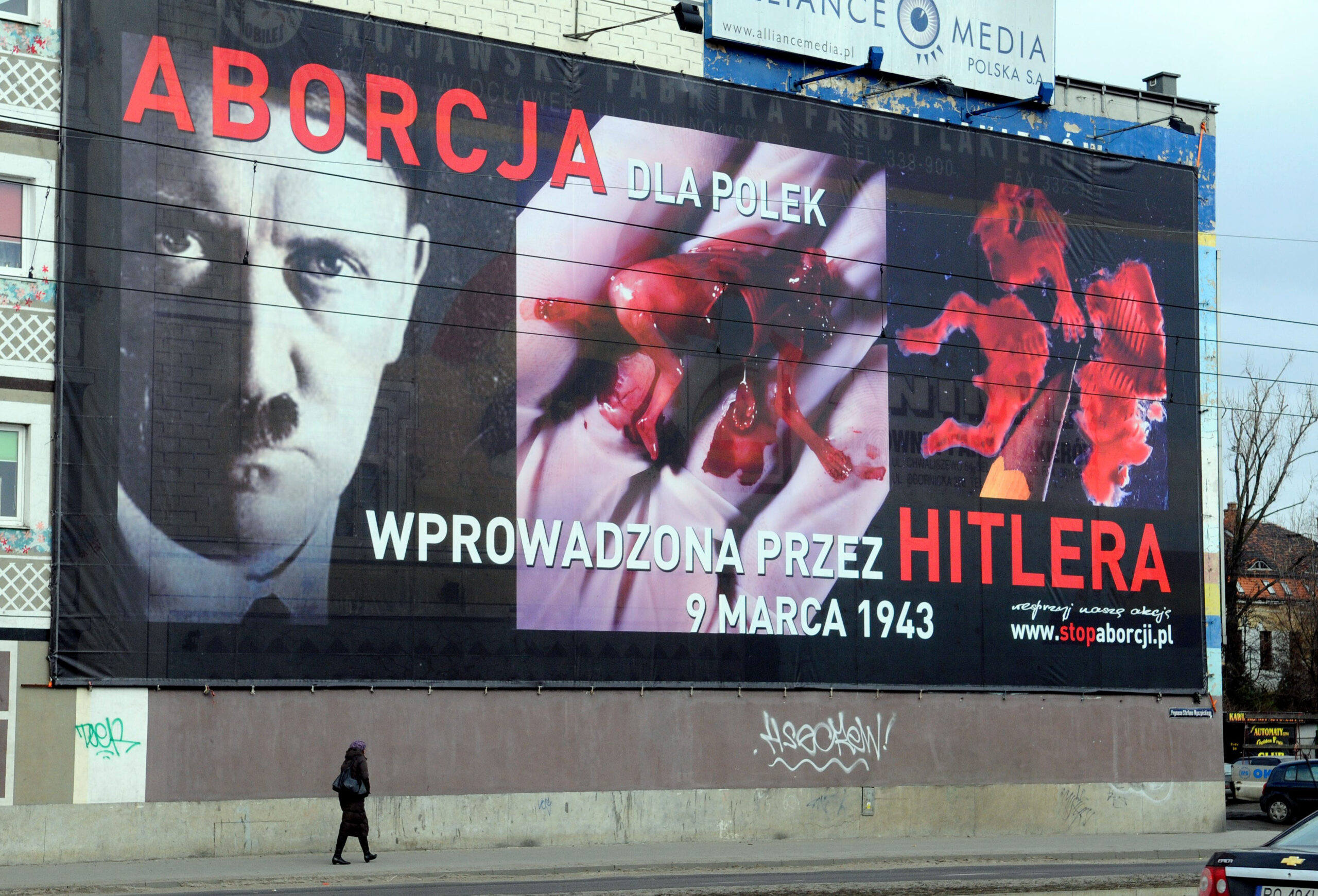 A passerby walks under a huge billboard hung by an anti-abortion group,  with images of Adolf Hitler alongside that of a torn, bloody fetus in the western town of Poznan, Poland, Wednesday, March 3, 2010. The inscription on the billboard  "Abortion for Poles: introduced by Hitler, March 9, 1943." refers to the upcomming anniversary of the introduction of legal abortions in Poland by the Nazi occupying forces during World War II. Today abortion is illegal in Poland. (AP Photo/Remigiusz Sikora) (Remigiusz Sikora)