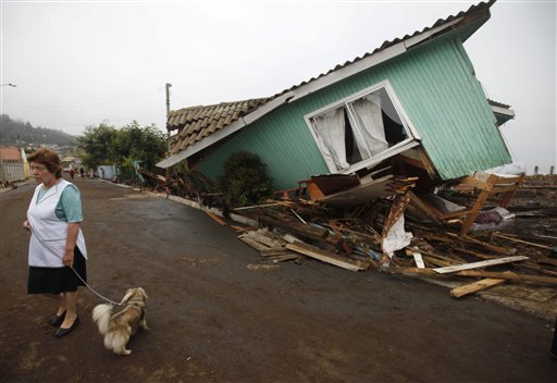 A woman stands in front of a damaged house after an earthquake in Pelluhue, some 322 kms, about 200 miles, southwest of Santiago, Sunday, Feb. 28, 2010. A 8.8-magnitude earthquake hit Chile early Saturday. (AP Photo/Roberto Candia) (AP)
