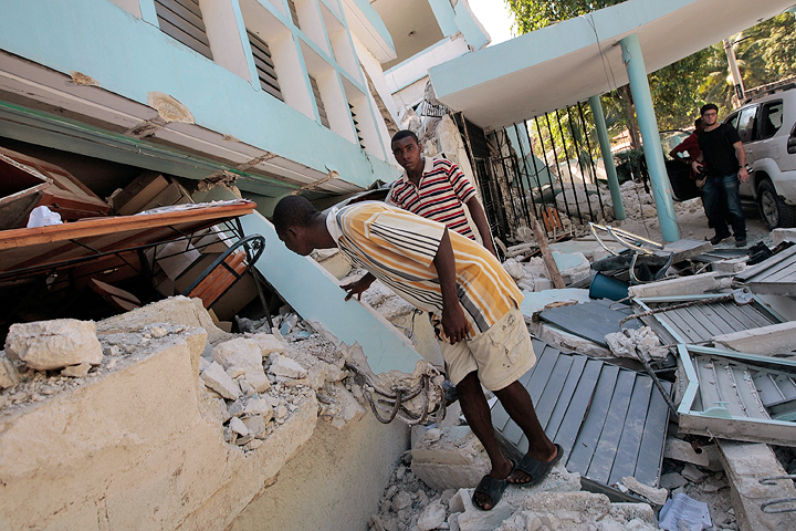 PORT AU PRINCE, HAITI - JANUARY 15:  Haitians as they pass by peek into the rubble of the College of St. Pierre that collapsed during the earthquake this week on January 15, 2010 in Port-au-Prince, Haiti.  Haiti is trying to recover from a powerful 7.0-strong earthquake that struck and devastated the nation on January 12.  (Photo by Chris Hondros/Getty Images) (Chris Hondros)