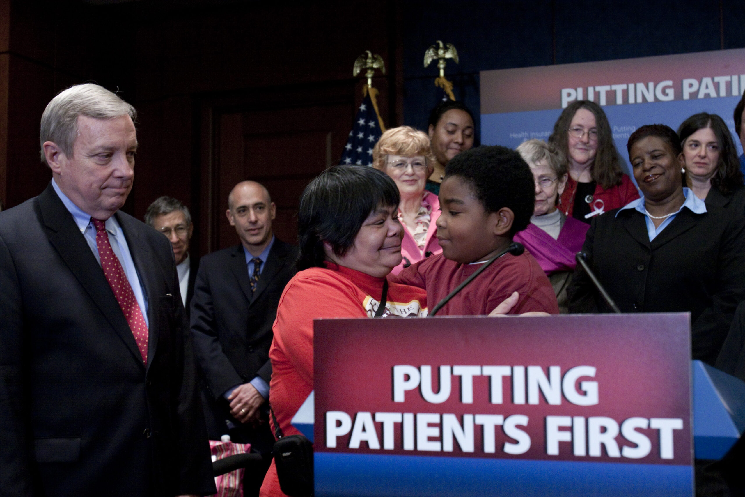 Senate Majority Whip Richard Durbin of Ill., left, looks on as Gina Owens hugs her grandson, Marcelas Owens from Seattle, Wash., whose mother, Tiffany Owens died after losing her job and health care, Thursday, March 11, 2010, during a health care news conference on Capitol Hill in Washington. (AP Photo/Harry Hamburg) (Associated Press)