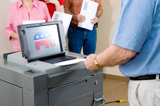 Closeup of senior man voting on an optical scanner with people waiting in line. (Lisa F. Young)