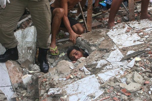 Carlos Eduardo Silva dos Santos, 24, peers out from under a wall where he is trapped as rescue workers try to free him after heavy rains in the Guarabita neighborhood of Rio de Janeiro, Wednesday, April 7, 2010.   The heaviest rains in Rio de Janeiro's history triggered landslides Tuesday that killed at least 95 people as rising water turned roads into rivers and paralyzed Brazil's second-largest city. (AP Photo/Jadson Marques, Agencia O Globo) (AP)