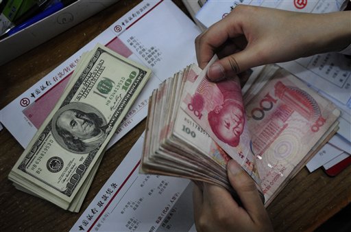 In this photo taken Tuesday, April 6, 2010, a bank clerk counts Chinese banknotes next to U.S. dollars on the counter at a bank in Hefei, in central China's Anhui province. U.S. Treasury Secretary Timothy Geithner is expected to press Beijing over its currency controls when he meets Vice Premier Wang Qishan in a sign the two sides are stepping up efforts to narrow their differences in the dispute. (AP Photo) **  CHINA OUT ** (AP)