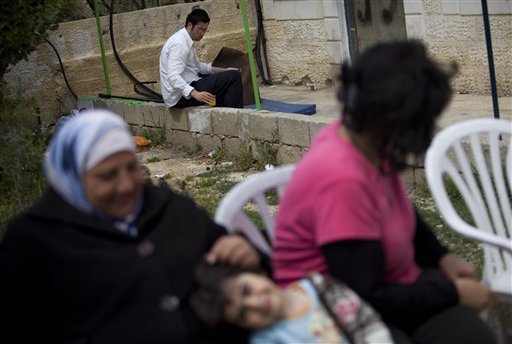 A Palestinian family sit outside a disputed house as Jewish settler rests at the house door, in the east Jerusalem neighborhood of Sheikh Jarrah, Thursday, March 25, 2010. Following a seemingly chilly reception at the White House, Benjamin Netanyahu is learning the hard way that he can't have it all. The Israeli leader will not likely be able to settle east Jerusalem with Jews and maintain strong relations with the Obama administration. He will be hard pressed to please his far-right coalition partners and still negotiate credibly with the Palestinians. (AP Photo/Bernat Armangue) (AP)