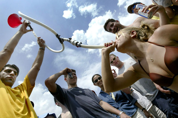 A college girl drinks beer through a funnel and pipe as thousands of college-age students gather on the infield in a traditional display of drunken fun on the day of the Preakness Stakes horse race at the Pimlico track in Baltimore, Maryland, May 15, 2004.