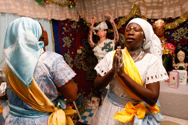 Messouma, a priest of the traditional African Bosson religion, prays with another follower of the faith at the altar of Mami Water after performing the ritual Ahouwe purification dance in Aniassue on the eastern Ivory Coast.