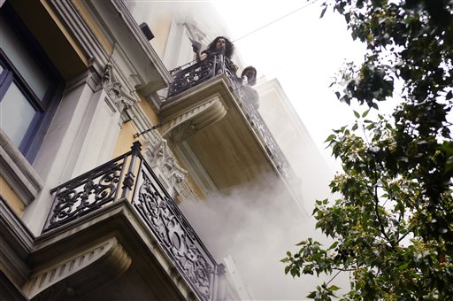 Bank employees, trapped by fire, look over the balcony ledge during an anti-government protest in central Athens, Wednesday, May 5, 2010. Three people died in the fire at the branch of Marfin Egnatia Bank, while the two women and two others were rescued. An estimated 100,000 people took to the streets Wednesday during a nationwide wave of strikes against spending cuts aimed at saving the country from bankruptcy  (AP Photo/Iakovos Hatzistavrou) ** GREECE OUT ** (AP)