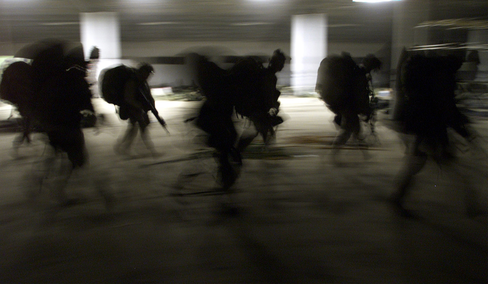 United States Marines from Bravo Co. of the 15th MEU (Marine Expeditionary Unity) march into a barracks in full battle gear as they arrive early November 29, 2001 at the US Marines forward base in southern Afghanistan. [Already hemmed into a shrinking swath of mountain and desert by nearly eight weeks of U.S. bombing and ground offensives by their Afghan foes, the Taliban now face another threat, hundreds of U.S. Marines pouring into a remote desert airstrip within striking distance of Kandahar, their spiritual cradle.] (Â© Jim Hollander / Reuters)