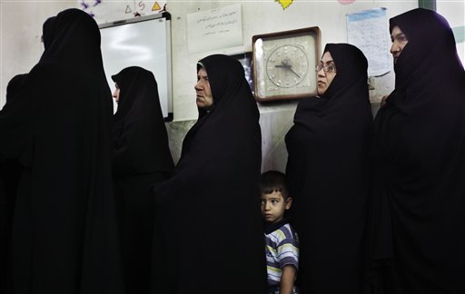 FILE - In this June 12, 2009 file photo, a young boy stands with a relative as she and others queue to cast their votes in the Iranian presidential elections at the Ershad mosque, on the outskirts of Tehran, Iran. Friday marks the first anniversary of the disputed re-election of President Mahmoud Ahmadinejad. (AP Photo/Ben Curtis, File) (AP)