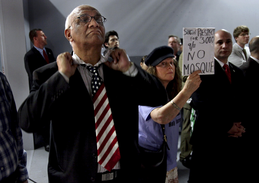 Arish Sahani, left, of New York, puts on an American Flag tie, and Linda Rivera, right, of New York, stand in opposition as groups planning a proposed mosque and cultural center near Ground Zero in Lower Manhattan to be named Cordoba House showed and spoke about their plans for the center at a community board meeting in New York Tuesday, May 25, 2010. Community members both for and against the plan spoke during the meeting.  (AP Photo/Craig Ruttle) (Craig Ruttle)