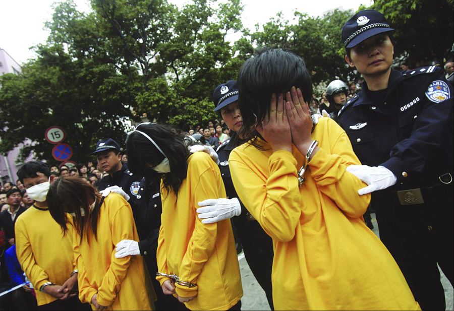 Police officers watch over prostitutes during a public parade in Shenzhen, south China's Guangdong province, November 29, 2006. China has ordered an investigation into a police-organised parade of 100 prostitutes and their clients in the southern city of Shenzhen, Hong Kong newspapers reported on Wednesday. Picture taken November 29, 2006. CHINA OUT REUTERS/China Daily (CHINA) (Â© China Daily China Daily Inform)
