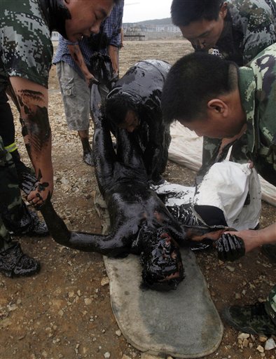 In this photo released by Greenpeace, a firefighter who was submerged in thick oil during an attempt to fix an underwater pump is brought ashore by his colleagues in Dalian, China on Tuesday, July 20, 2010. Crude oil started pouring into the Yellow Sea off a busy northeastern port after a pipeline exploded late last week, sparking a massive 15-hour fire. The government says the slick has spread across a 70-square-mile (180-square-kilometer) stretch of ocean. (AP Photo/Jiang He, Greenpeace) **  NO SALES NO ARCHIVE  ** (AP)