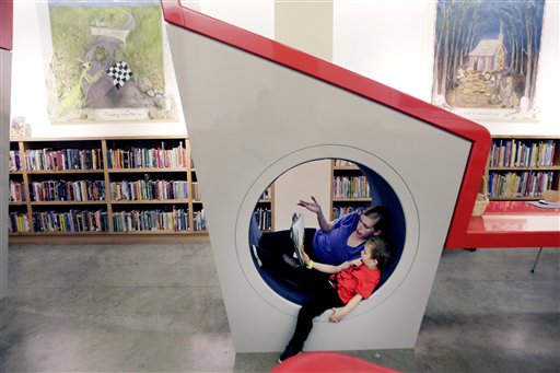 In this photo made Friday, June 25, 2010, Prisilla Gluckman reads to her four-year-old son Oscar Gluckman at Bookmarks, a Dallas Public Library Branch at NorthPark Center mall in Dallas. In the first two months after it opened in NorthPark Center, Bookmarks issued more than 700 library cards.  Two years after it opened at the mall, the library for kids 12 and under has an inventory of about 5,000  and circulates as much as branches eight times that size with both adult and children's books. (AP Photo/LM Otero) (AP)