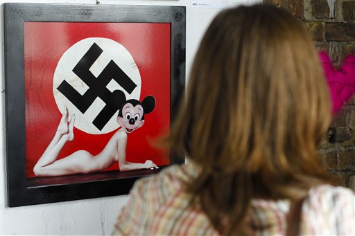 A woman stands in front of a artwork by Italian artist Max Papeschi at the exhibition 'Abnormal Nudes' at the alternative art house Tacheles in Berlin on Tuesday, July 13, 2010. The  art poster hung on a Polish street that blends Mickey Mouse's innocent image with that of a swastika and a nude woman's body is causing a stir in Poland, where memories of suffering inflicted by Nazi Germany remain strong.  The poster, which went up last month in the western city of Poznan just steps from an old synagogue, is an Italian artist's critical take on what he calls the "horrors" of the American lifestyle and is one work in a contemporary art exhibition that is to open in the fall. (AP Photo/Markus Schreiber) (AP)