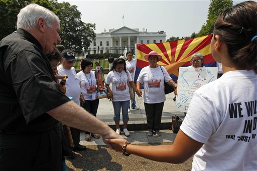 Hispanic community members, some from Phoenix, hold hands in prayer to protest against SB1070, Arizona's immigration law, during a vigil in front of the White House in Washington Wednesday, July 7, 2010.(AP Photo/Alex Brandon) (AP)