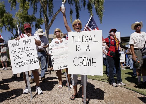 FILE - In this June 5, 2010 file photo, Judy Schulz, center, cheers as her husband Richard Schulz, left, both of Glendale, Ariz., joined hundreds supporting Arizona's new law on illegal immigration as they listen to speakers near the capitol in Phoenix. At the heart of the debate over Arizona's tough new immigration law is frustration with how the U.S. deals with the estimated 11 million illegal immigrants within its borders. The federal government says its policy is to focus on dangerous, criminal immigrants, not the average worker who is just trying to earn a living and keeps his nose clean. There is just no way the government can find, arrest and deport so many people, they argue. (AP Photo/Ross D. Franklin, File) (AP)