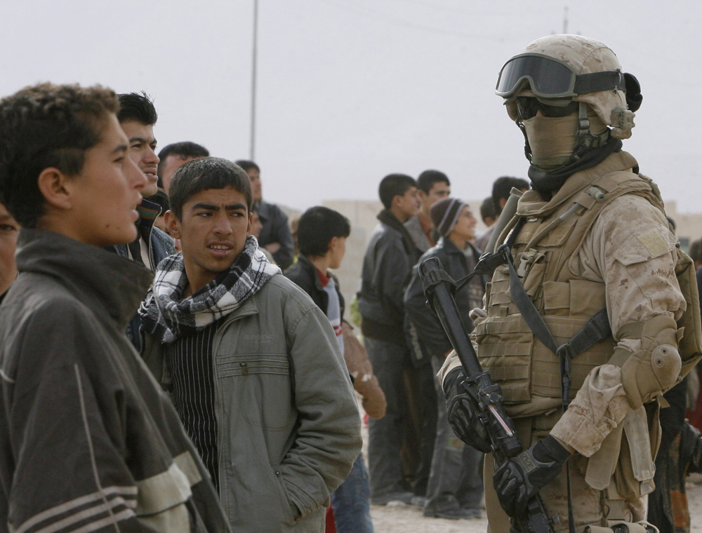 Residents look at a U.S. marine providing security to international election observers in Sinjar, 390 km (240 miles) northwest of Baghdad, January 31, 2009. Iraqis held their most peaceful election since the fall of Saddam Hussein on Saturday, and voting for provincial councils ended without a single major attack reported anywhere in the country.            REUTERS/Erik de Castro  (IRAQ) (Â© Erik De Castro / Reuters)