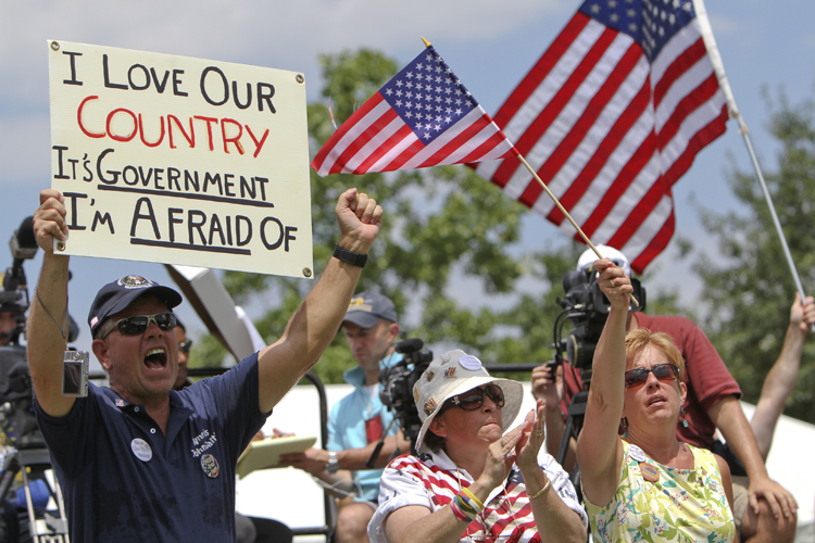People hold signs and wave flags during the "Uni-Tea" Tea Party rally at Independence Mall in Philadelphia on Saturday July 31, 2010. (AP Photo/ Joseph Kaczmarek) (Joseph Kaczmarek)