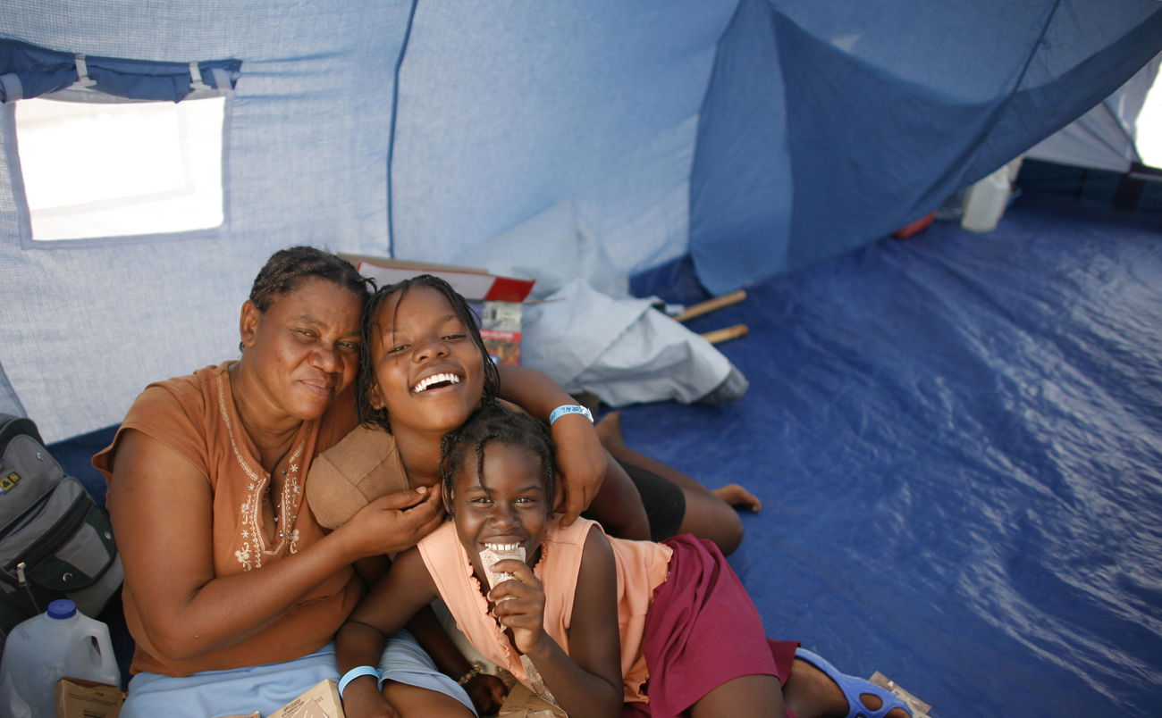 Earthquake survivors pose for a picture in their new tent in Corail, just outside Port-au-Prince, after being relocated there from Petionville Golf Club April 14, 2010. Haiti's government and foreign aid agencies started an operation on Saturday to move thousands of earthquake survivors to a safer refuge to avoid the risk of mudslides and flooding during the rainy season. REUTERS/Eduardo Munoz (HAITI - Tags: DISASTER SOCIETY) (Â© Eduardo Munoz / Reuters)