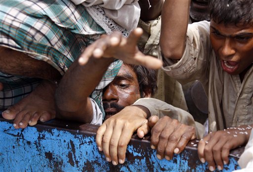 A flood survivor jostles for position as they try to reach for relief goods in flood hit Muzaffargarh district, Punjab province,  Pakistan on Thursday Aug. 19, 2010. Weeks after massive downpours first battered northern Pakistan, submerging tens of thousands of square miles, killing near 1,500 people and leaving millions homeless, those floodwaters are still sweeping down river and through the south, adding one more layer of misery to people long accustomed to hardship. (AP Photo/Aaron Favila) (AP)