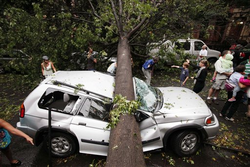 Residents in the Park Slope neighborhood in the Brooklyn borough of New York circle around a car crushed by a fallen tree, Thursday, Sept. 16, 2010. A brief but severe storm has swept through New York City, uprooting trees and damaging cars. (AP Photo/Mark Lennihan) (AP)