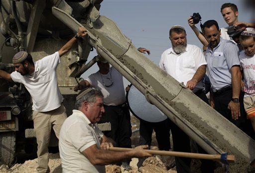 Jewish settlers participate in a cornerstone laying ceremony for a daycare center at the West Bank Jewish settlement of Kiryat Netafim, Sunday, Sept. 26, 2010. With a midnight deadline looming, Israel's prime minister on Sunday called on West Bank settlers to "show restraint" after the end of a government-ordered construction slowdown, attempting to lower tensions with the Palestinians and prevent a breakdown in newly relaunched Mideast talks. (AP Photo/Ariel Schalit) (AP)