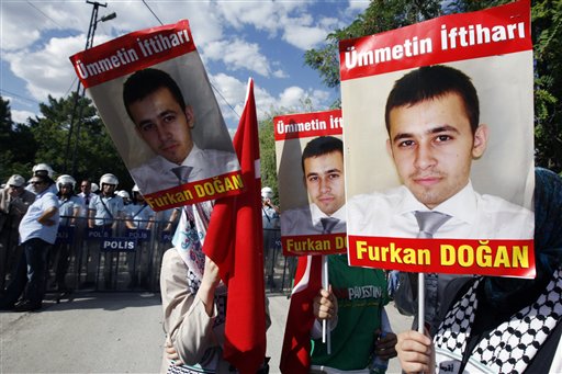 Pro-Palestinian Turks hold posters of Furkan Dogan, the American-Turkish citizen who was born in the U.S. in 1991and one of nine activists killed May 31, 2010, during a pre-dawn military takeover of six aid ships by Israeli forces in the international waters of the Mediterranean Sea, before they clash with  riot police as Israeli volleyball team play against Sebia for CEV Women's European League tournament in Ankara, Turkey, Saturday, July 24, 2010. (AP Photo/Burhan Ozbilici) (AP)