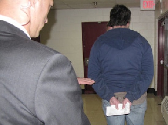A private security guard watches handcuffed Alaska Dispatch Editor Tony Hopfinger
