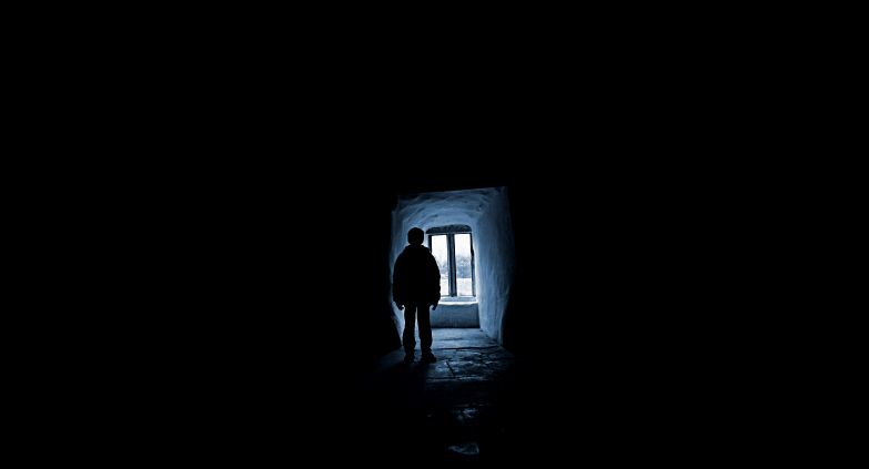 Blue toned picture a a young boy silhouetted by the light falling through an old window. Has film grain at ful size. (Duncan P Walker)