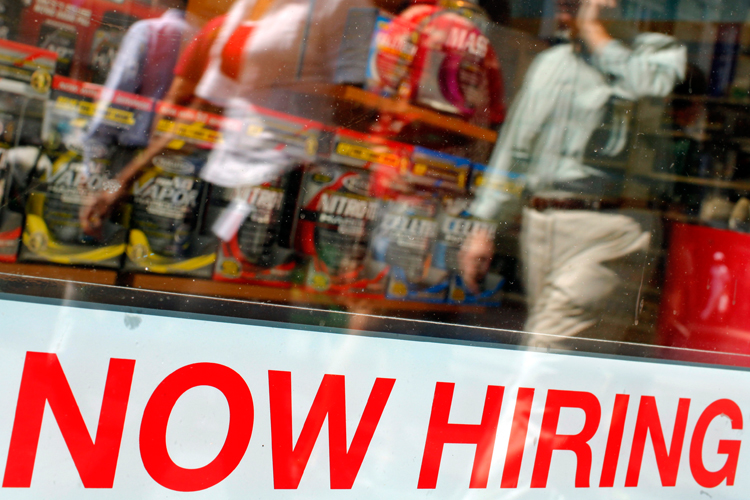A "Now Hiring" sign in the window of a GNC store in Boston.