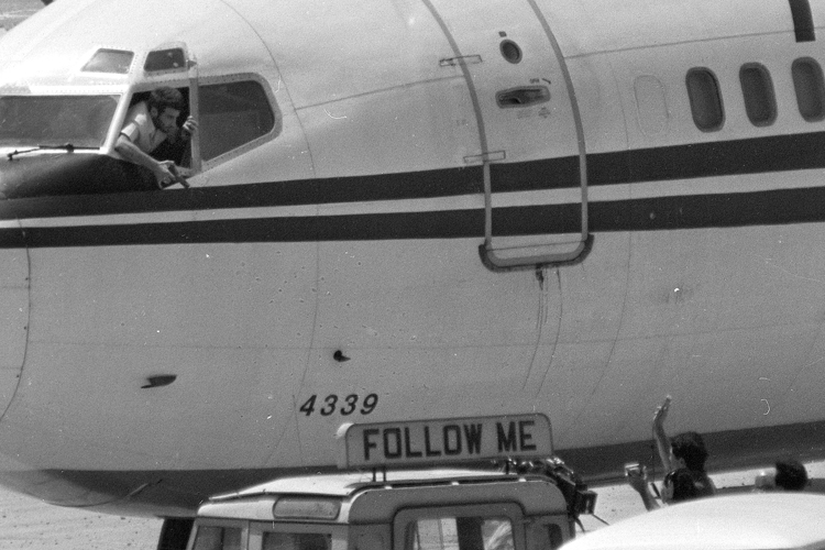 A hijacker points his pistol from the cockpit of TWA Flight 847 as an ABC news crew approaches the jet for an interview at Beirut International Airport on June 19, 1985.