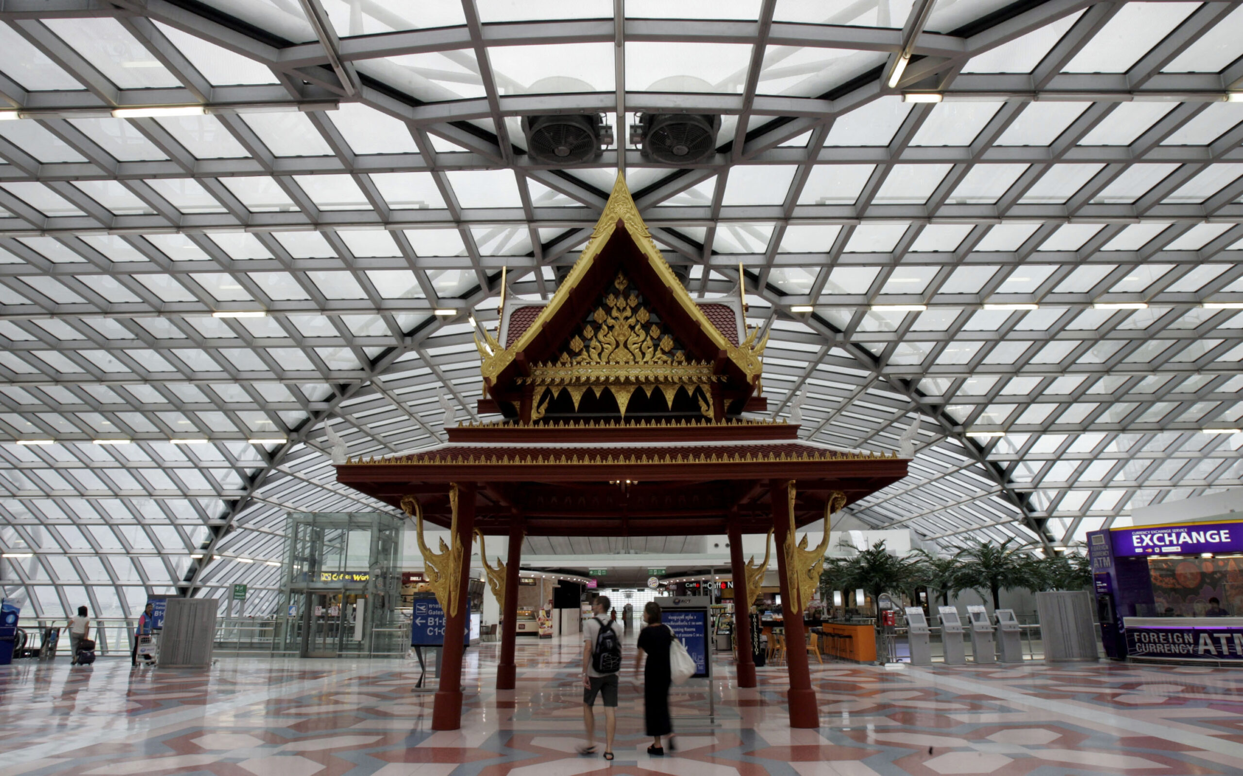 In this photo taken Tuesday, Sept. 8, 2009, two tourists stroll past a Thai-styled pavillian at departure hall at Suvarnabhumi International Airport in Bangkok, Thailand. The Tourism Authority of Thailand is offering five couples fully paid trips to the country's most popular cities and beaches. In return, they will be asked to blog, chat and tweet about their holiday in a bid to win a grand prize of $10,000, a BlackBerry and a video camera. Thailand's tourism industry is facing its worst crisis in years, with foreign arrivals down 15 percent so far this year because of political upheaval and the global recession. (AP Photo/Apichart Weerawong) (Apichart Weerawong)