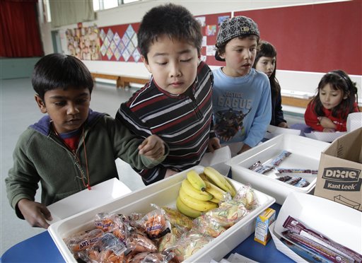Fairmeadow Elementary School second grade student Jonathan Cheng, center, looks at fruits and vegetables during a school lunch program in Palo Alto, Calif., Thursday, Dec. 2, 2010. More children would eat lunches and dinners at school under legislation passed Thursday by the House and sent to the president, part of first lady Michelle Obama's campaign to end childhood hunger and fight childhood obesity. The $4.5 billion bill approved by the House 264-157 would expand a program that provides full meals after school to all 50 states. It would also try to cut down on greasy foods and extra calories by giving the government power to decide what kinds of foods may be sold in vending machines and lunch lines. (AP Photo/Paul Sakuma) (AP)