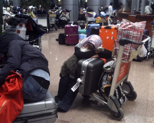 Passengers stranded by the curfew and thus prevented from entering the Egyptian capital sleep at Cairo airport, early Sunday, Jan. 30, 2011. (AP Photo/Bertrand Combaldieu) (AP)