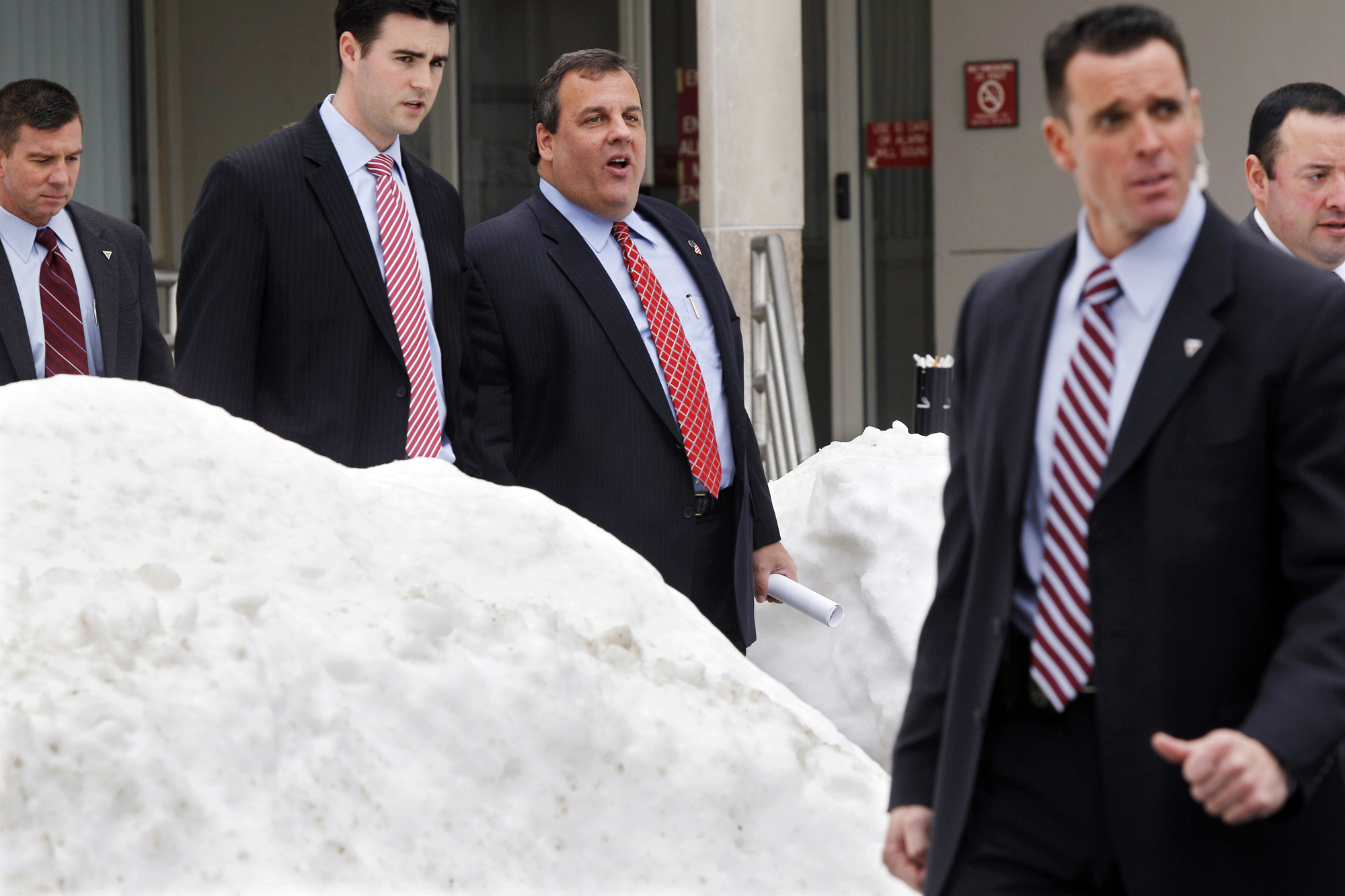 New Jersey Gov. Chris Christie, third from left, walks past piles of snow with staff and security as he leaves an event Friday, Dec. 31, 2010, in Freehold, N.J., where he talked about last weekend's snow storm. Christie left for Florida and a family vacation at Disney World last Sunday. (AP Photo/Mel Evans) (Mel Evans)