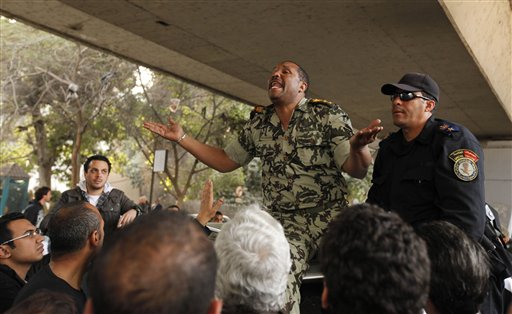 An unidentified high ranked military official, center, and a police officer explain to the crowd that army, police and the citizens must work hand in hand, in Cairo, Sunday Jan. 30, 2011. The Arab world's most populous nation appeared to be swiftly moving closer to a point at which it either dissolves into widespread chaos or the military expands its presence and control of the streets. (AP Photo/Victoria Hazou) (AP)