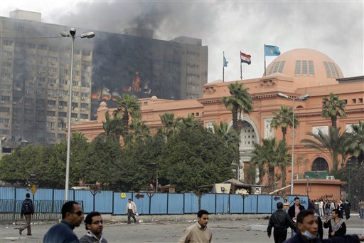 The Egyptian museum is seen intact, right, as smoke billows from the ruling National Democratic party building, torched by anti government protesters overnight, in central Cairo, Egypt, Saturday, Jan. 29, 2011. (AP Photo/Ben Curtis) (AP)