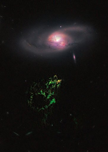 This handout photo provided by NASA, taken April 12, 2010 by the Hubble Space Telescope, shows an unusual, ghostly green blob of gas appears to float near a normal-looking spiral galaxy. NASA released Monday the Hubble Space Telescopes first picture of the mysterious giant glowing green blob of gas called Hannys Voorwerp.  The blob is the size of our Milky Way galaxy and is 650 million light years away. Each light year is about 6 trillion miles. The blob was discovered in 2007 by Dutch school teacher Hanny van Arkel. (AP Photo/Hubble Space Telescope Science Institute) (AP)